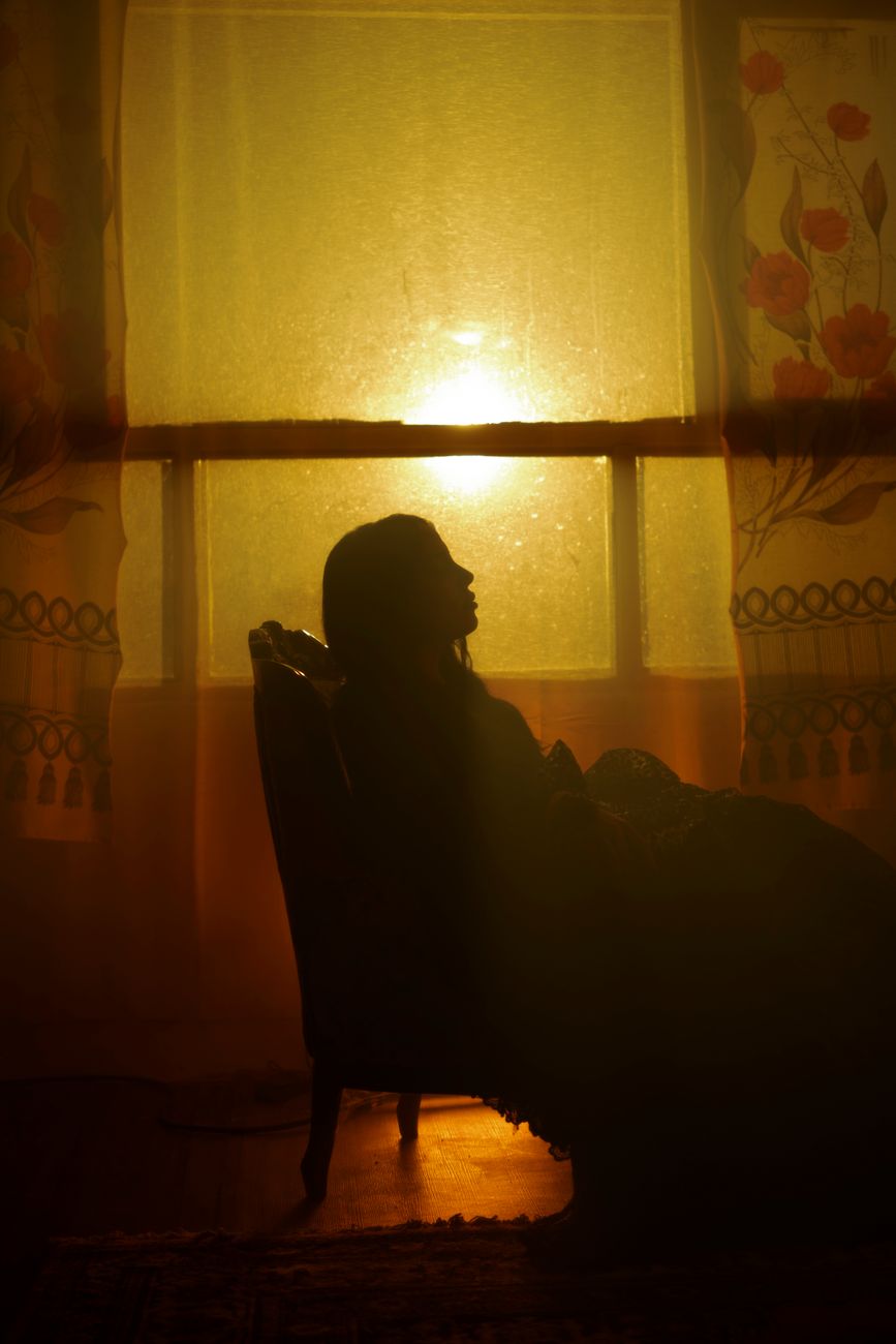 silhouette of a woman sitting in an armchair in a dark room