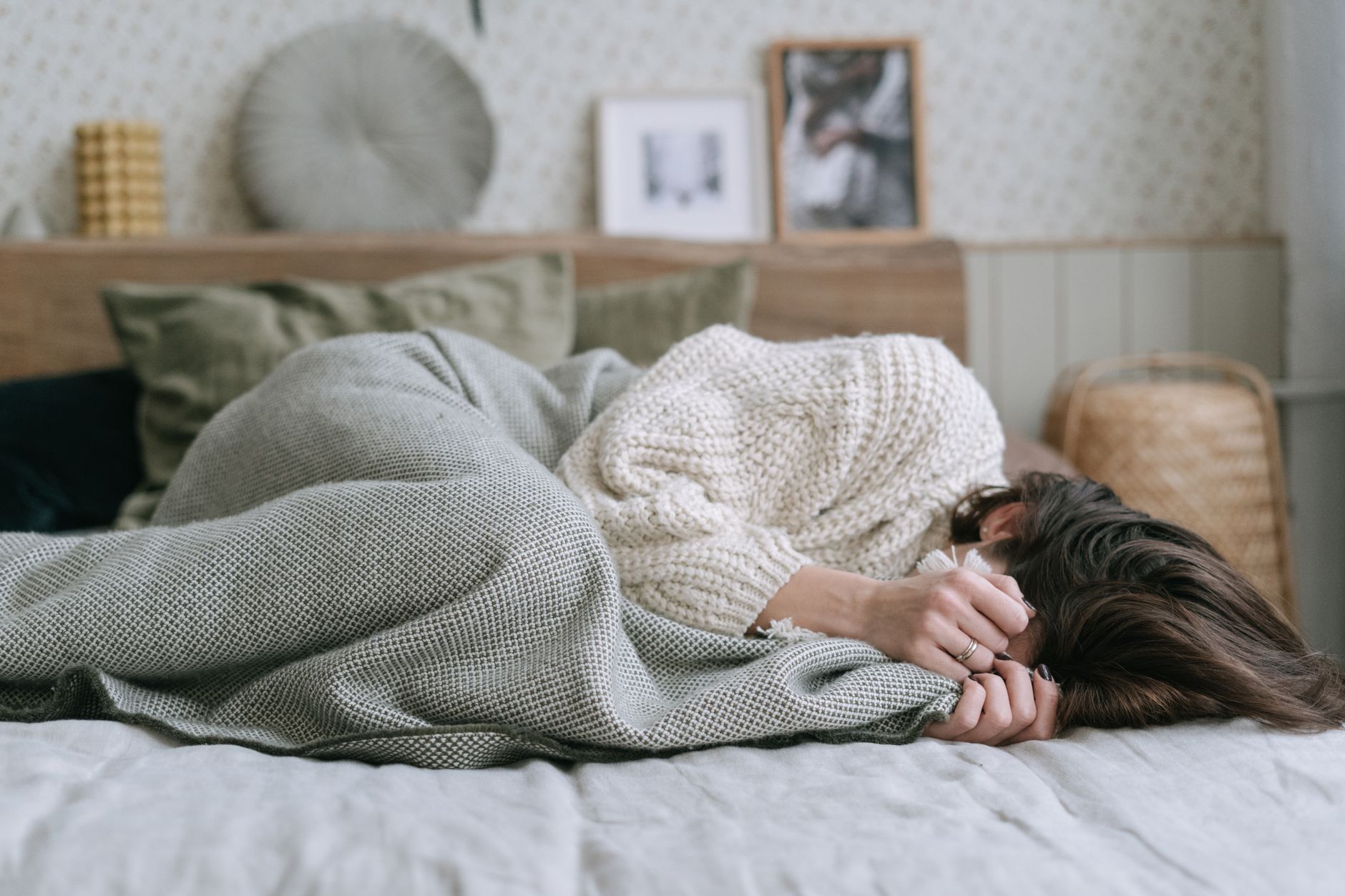 a woman in white knitted sweater lying on the bed